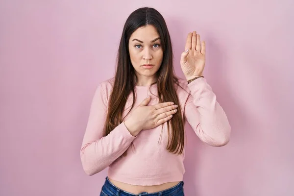 Joven Morena Pie Sobre Fondo Rosa Jurando Con Mano Pecho — Foto de Stock