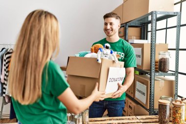 Genç İspanyol gönüllü çift gülümsüyor. Yardım merkezinde bağışlanacak oyuncaklarla birlikte mutlu bir kutuda tutuyorlar..