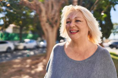 Parkta kendine güvenen orta yaşlı sarışın bir kadın.