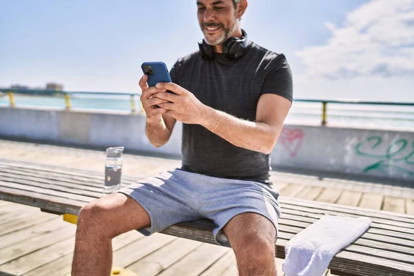中年人穿着运动服 在海滨用智能手机 — 图库照片