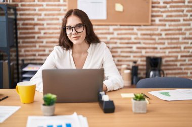 Ofiste çalışan genç bir iş kadını dizüstü bilgisayar kullanıyor.