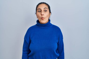 Soyutlanmış arka planda duran genç İspanyol kadın dudaklarıyla balık suratı yapıyor, çılgınca ve komik bir jest. Komik ifade. 