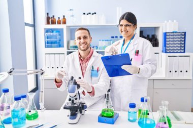 Laboratuvarda çalışan iki genç insan mutlu mesut gülümsüyor. 