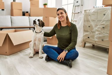 Genç bayan gülümsüyor. Kendine güvenen, kucaklayan köpek evde.
