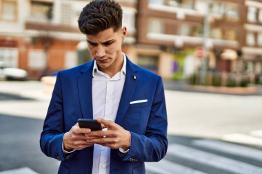 Sokakta akıllı telefon kullanan genç bir adam.