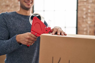 Genç İspanyol adam yeni evinde kendine güvenen bir karton kutu paketliyor.