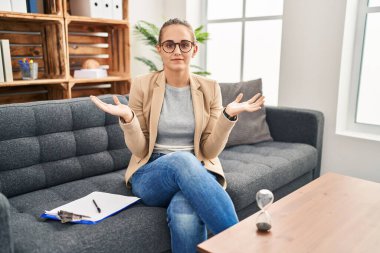Young woman working at consultation office clueless and confused with open arms, no idea concept. 