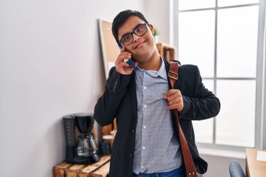 Down sendromlu iş adamı ofiste akıllı telefondan konuşuyor.