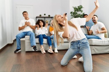 Bir grup genç arkadaş evde mikrofon kullanarak şarkı söylüyor..