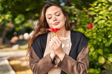 Genç, güzel İspanyol kadın gülümsüyor. Parktaki kendine güvenen çiçek gibi.