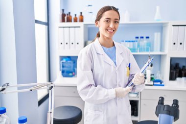 Genç ve güzel İspanyol bilim adamı. Laboratuvarda elinde bir pano tutarak gülümsüyor.