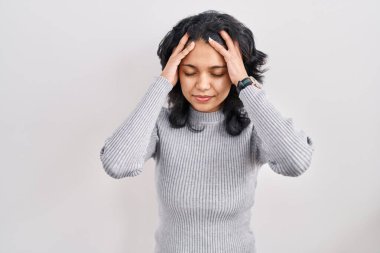 Koyu renk saçlı İspanyol bir kadın, izole bir arka planda duruyor, elleri başının üstünde, stres yüzünden başı ağrıyor. migren ağrısı. 