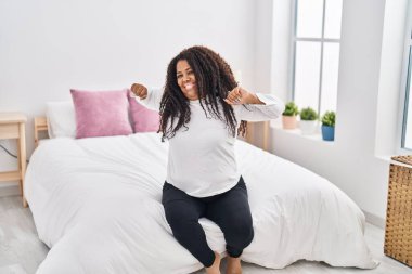 Afrikalı Amerikalı bir kadın yatak odasında kollarını açarak uyanıyor.