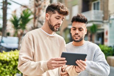 Young couple using touchpad standing together at street