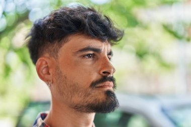 Young hispanic man looking to the side with relaxed expression at street