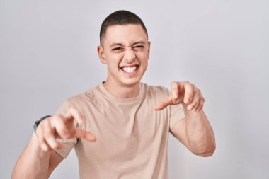 Soyutlanmış arka planda duran genç adam gülüyor. Pençe hareketlerini kedi gibi yapıyor. Agresif ve seksi bir ifade. 