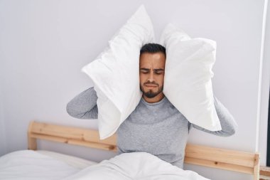 Genç İspanyol adam yatak odasındaki gürültü için kulaklarını kapatıyor.