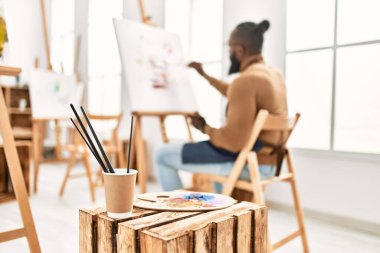 Arkaya bakan genç Afrikalı Amerikalı ressam sanat stüdyosunda resim çiziyor..