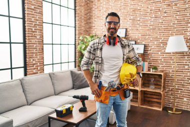 Genç İspanyol işçi gülümseyerek evde duruyor.