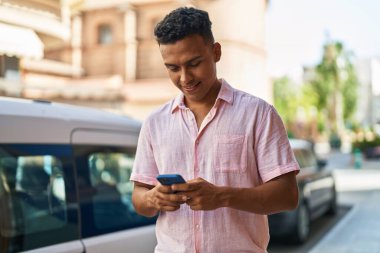 Sokakta akıllı telefon kullanan, kendine güvenen genç Latin adam.