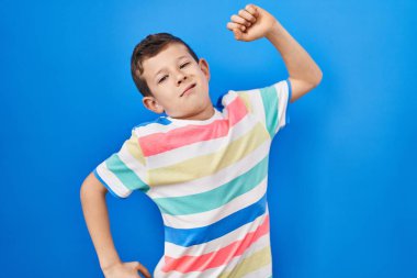 Mavi arka planda dikilen genç beyaz çocuk, yorgun ve rahat, uykulu ve sabahın erken saatleri için esniyor. 