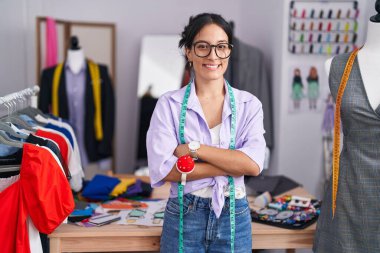 Genç ve güzel İspanyol kadın terzi dükkanında kollarını kavuşturup gülümsüyor.