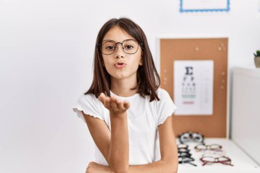 Gözlüklü genç İspanyol kız kameraya bakıyor ve havada bir öpücük savuruyor. Güzel ve seksi. aşk ifadesi. 