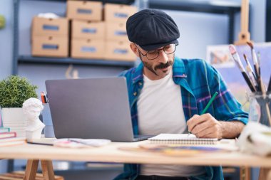 Genç İspanyol ressam sanat stüdyosunda dizüstü bilgisayarla çizim yapıyor.