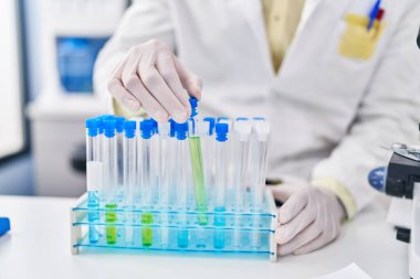 Laboratuvarda test tüpleri tutan bilim adamı üniforması giyen İspanyol bir genç.