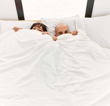 Yatak odasındaki yatakta çarşafla yüzünü örten genç İspanyol çift..