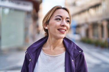 Gülümseyen genç bir kadın sokağın kenarına bakıyor kendinden emin.