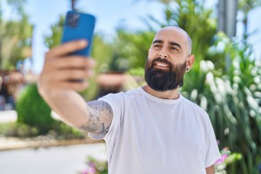 Young bald man smiling confident making selfie by the smartphone at park