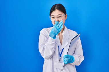 Laboratuvarda çalışan Çinli genç bir kadın pis ve iğrenç bir koku alıyor. Nefesini burnunda tutuyor. Kötü kokuyor. 