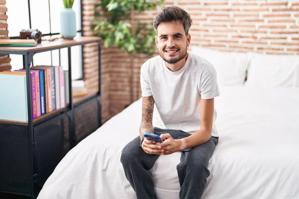 Young Hispanic Man Using Smartphone Sitting Bed Bedroom — Foto de Stock