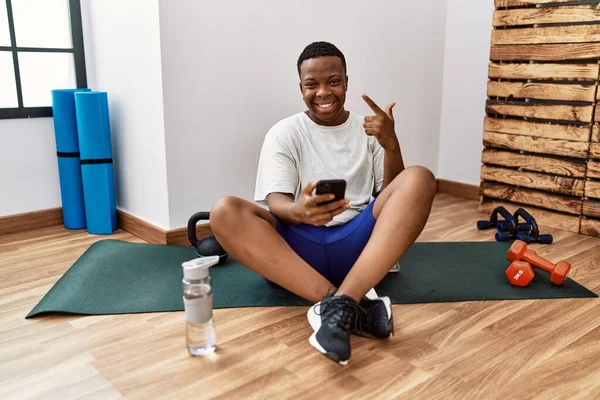 Young African Man Sitting Training Mat Gym Using Smartphone Cheerful — Stok fotoğraf
