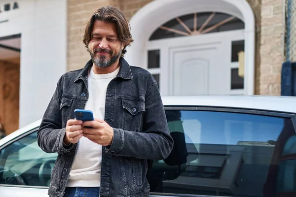 中年男子在街上用智能手机靠在汽车上 — 图库照片