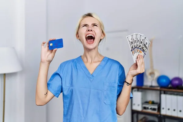 Joven Fisioterapeuta Mujer Sosteniendo Tarjeta Crédito Billetes Dólares Enojado Loco — Foto de Stock