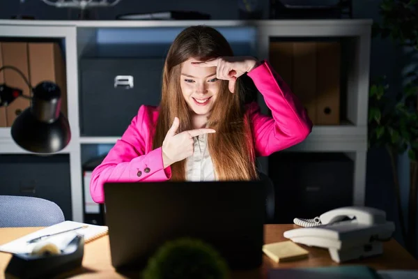 夜のオフィスで働く若い白人女性は 幸せな顔をした手と指でフレームを作り笑顔 創造性と写真の概念 — ストック写真