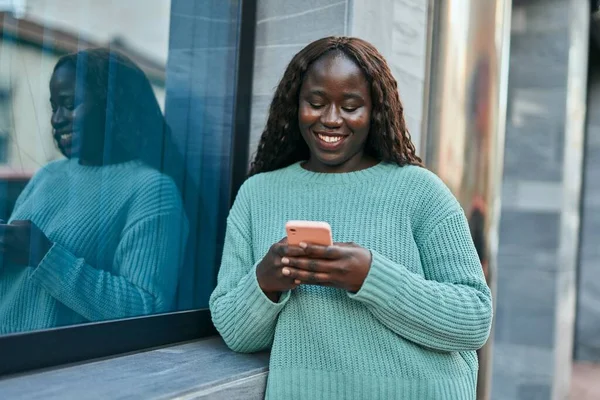Młoda Afrykanka Uśmiechnięta Szczęśliwa Korzystając Smartfona Opierającego Się Ścianie — Zdjęcie stockowe