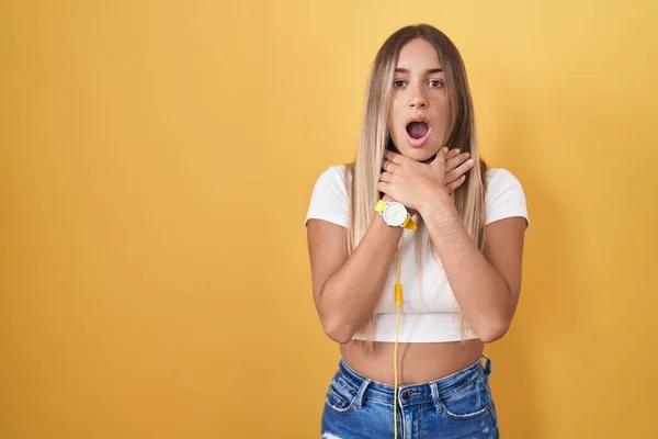 Young Blonde Woman Standing Yellow Background Wearing Headphones Shouting Suffocate — Foto Stock