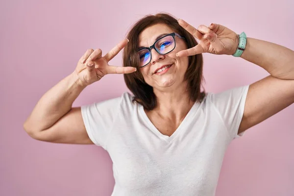 Medelåldern Latinamerikansk Kvinna Står Över Rosa Bakgrund Gör Fred Symbol — Stockfoto