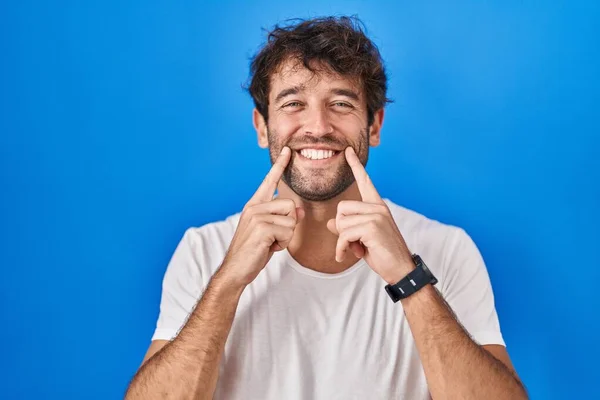Hispánský Mladý Muž Stojí Nad Modrým Pozadím Usmívá Otevřenými Ústy — Stock fotografie