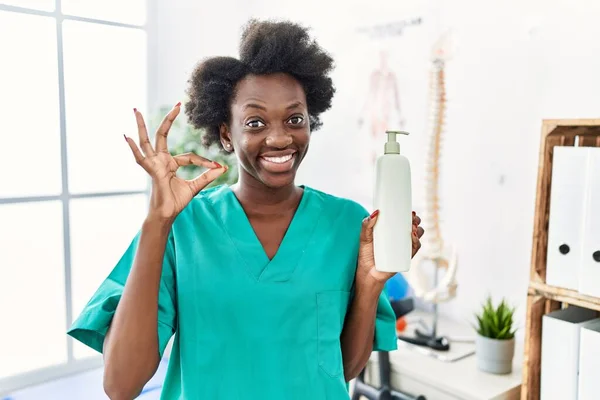 African Young Physiotherapist Woman Holding Massage Body Lotion Doing Sign — Photo