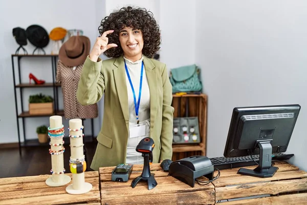 小売ブティックでマネージャーとして働く若い中東の女性は 指を見てカメラで小さなサイズの看板を行う手で笑顔と自信を持ってジェスチャー 概念を測定し — ストック写真