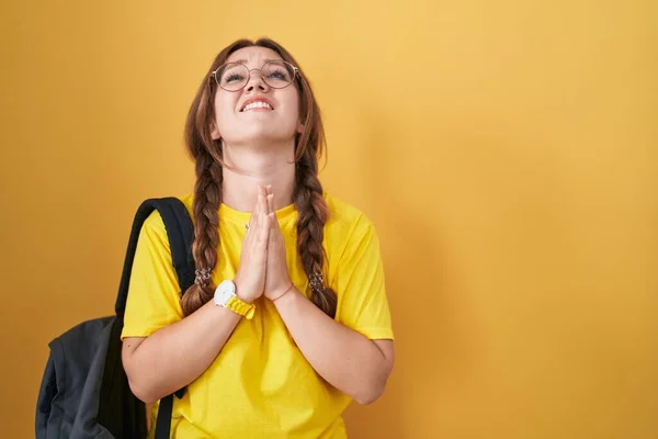 Junge Kaukasische Frau Mit Studentenrucksack Vor Gelbem Hintergrund Bettelt Und — Stockfoto