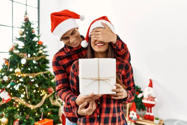 Fiatal Latin Férfi Meglepi Barátnőjét Karácsonyi Ajándékkal Otthon — Stock Fotó
