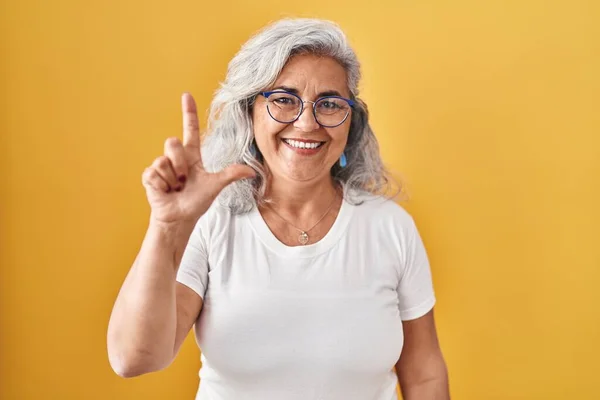 Sarı Arka Planda Gri Saçlı Orta Yaşlı Bir Kadın Iki — Stok fotoğraf