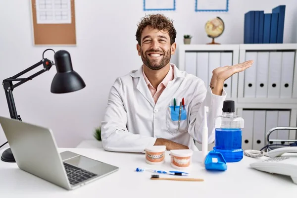 Jonge Spaanse Tandarts Werkt Medische Kliniek Glimlachend Vrolijk Presenteren Wijzen — Stockfoto