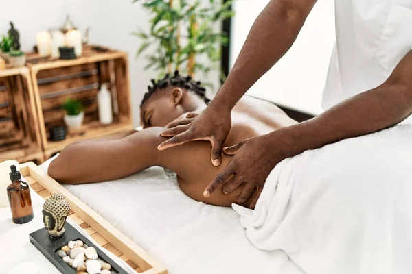 African american woman reciving back massage at the clinic.