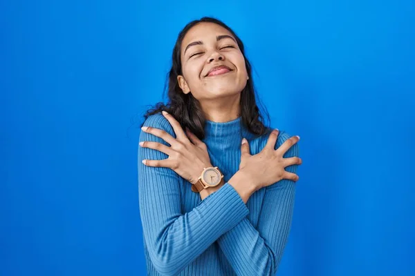 Mujer Brasileña Joven Pie Sobre Fondo Azul Aislado Abrazándose Feliz — Foto de Stock